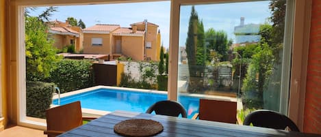 A patio with a pool, outdoor furniture, and a view of neighboring buildings.