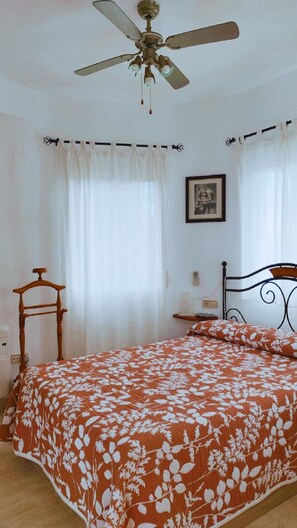 A bedroom with a bed, a ceiling fan, a bedside table, a chair, and a framed picture on the wall. - Villa San Antonio with a private pool (Peníscola)