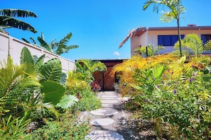 A garden pathway leading to a building with a thatched roof. - SINA BUNGALOWS PUERTO VIEJO (Cahuita)