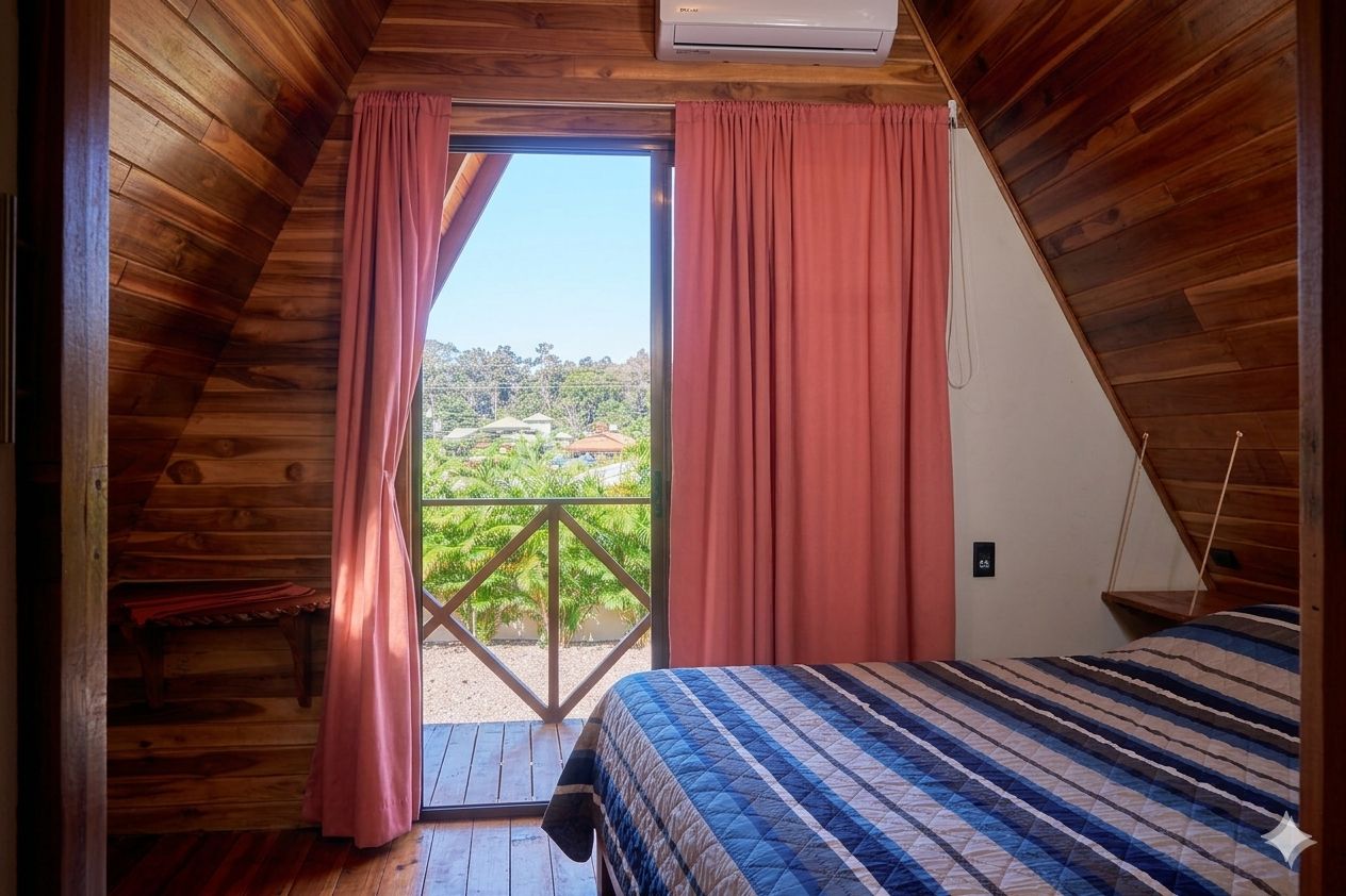 Un dormitorio con cama, ventana con cortinas y vistas al verdor exterior.