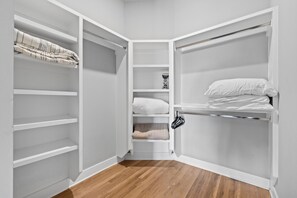 Ein begehbarer Kleiderschrank mit offenen Regalen, einer Kleiderstange und einem ausgeklappten Bett.