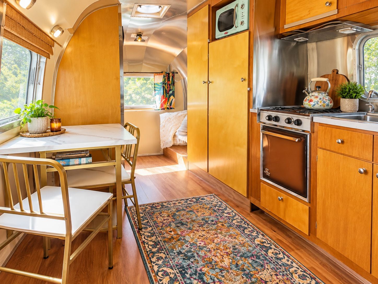 A compact kitchen with a stove, oven, microwave, and wooden cabinets.