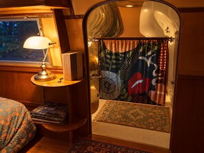 Une pièce confortable avec un lit, une lampe, une bibliothèque et une porte donnant sur une salle de bain équipée d’un rideau de douche.