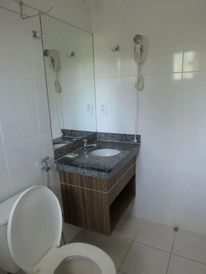 Un baño con inodoro, lavamanos con espejo y ducha.
