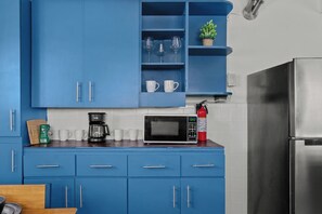 A kitchen with blue cabinets, a microwave, a coffee maker, and a fire extinguisher. - Santurce Blue 2BR | Near Beach & La Placita (San)