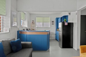 Ein gemütlicher, kompakter Wohnraum mit Küchenzeile, einer Couch und einem Kühlschrank.