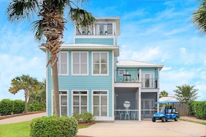 A two-story house with a balcony, a garage, and a golf cart parked in front. - Sunkissed! Oceanview! Pool! Golf Cart! 6 Bedrooms (Destin)