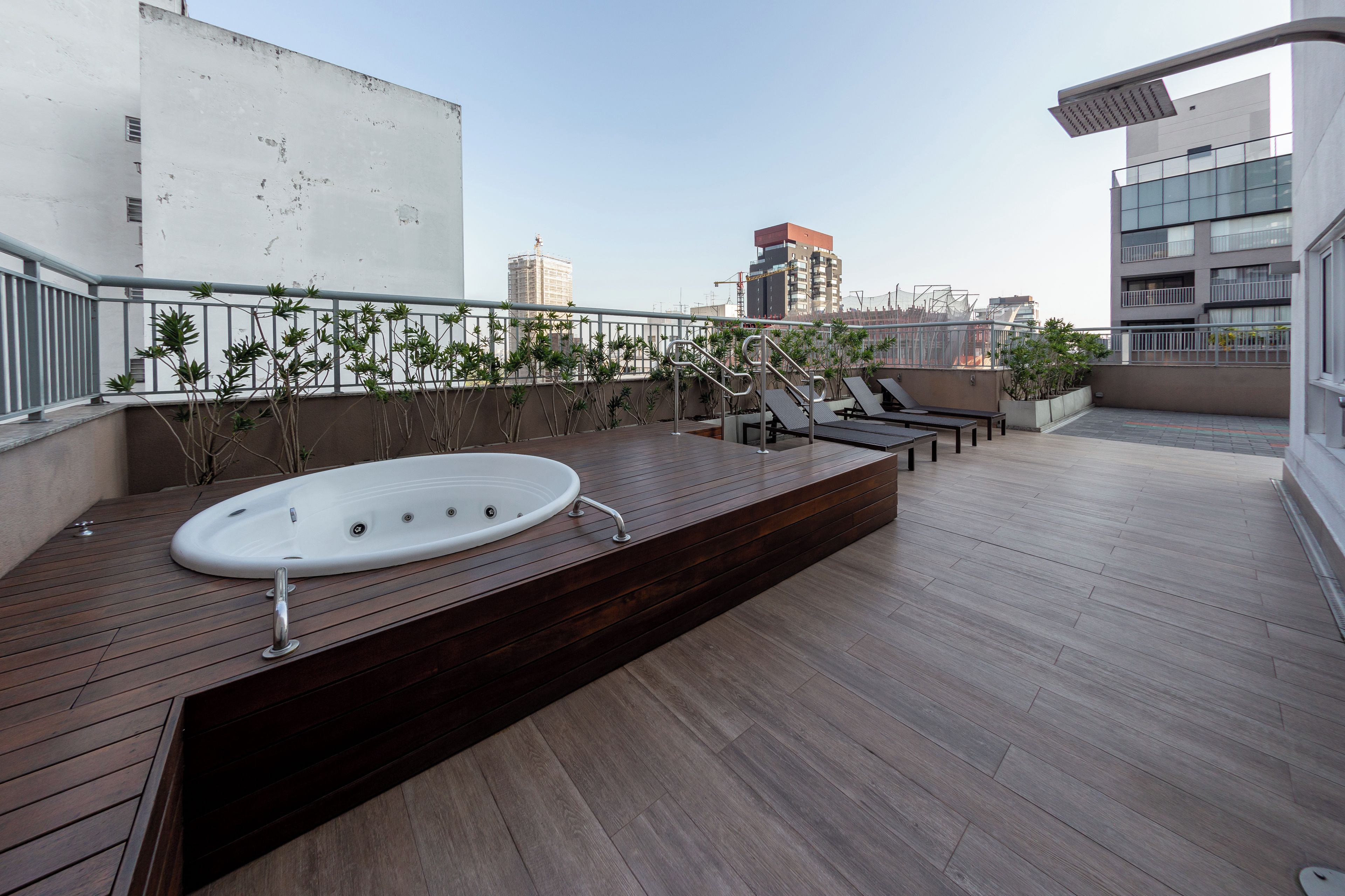 A rooftop terrace with a hot tub, lounge chairs, and potted plants.