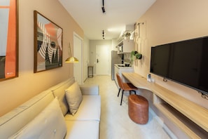 Een moderne woonkamer met een bank, een televisie en een eethoek met stoelen.