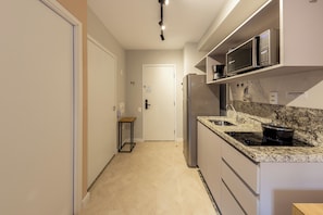 Een moderne keuken met een ingebouwde magnetron, fornuis en een granieten aanrecht.