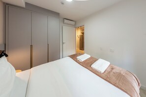 Een hotelkamer met een bed, een kledingkast en een badkamer, zichtbaar door een open deur.