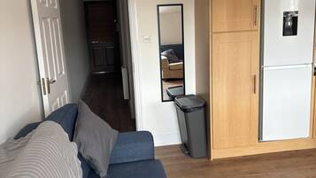 Ein Zimmer mit einem blauen Sofa, einem Holzschrank, einer weißen Tür und einem Spiegel.
