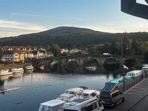 A river with boats, a stone bridge, and buildings along the riverbank.