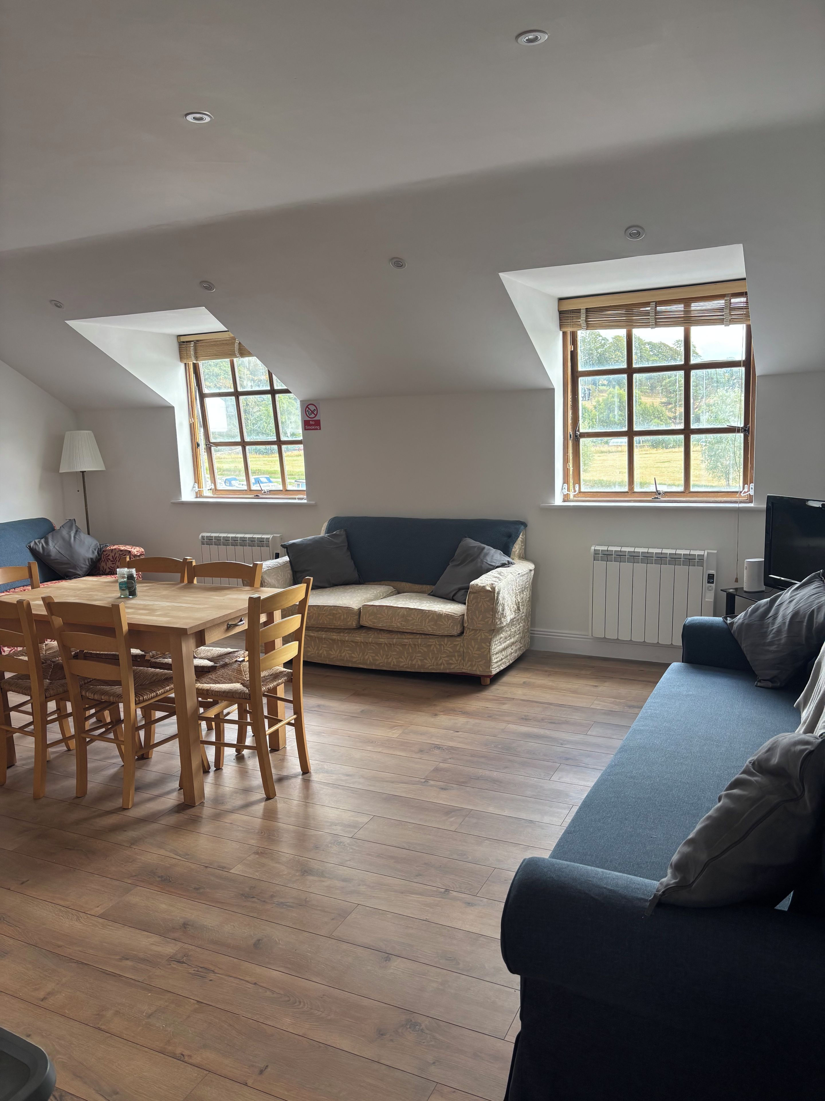 A room with a dining table, chairs, a sofa, and a television.