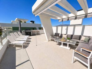 Eine Dachterrasse mit Liegestühlen, einer Sofagruppe und einem Esstisch.