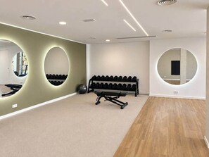 Ett gym med träningsutrustning, en bänk och ett väggmonterat ställ för hantlar.
