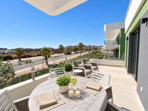 Een balkon met buitenmeubilair, een tafel en een potplant.