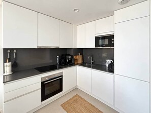 Eine moderne Küche mit weißen Schränken, einer schwarzen Arbeitsplatte und einem eingebauten Backofen.