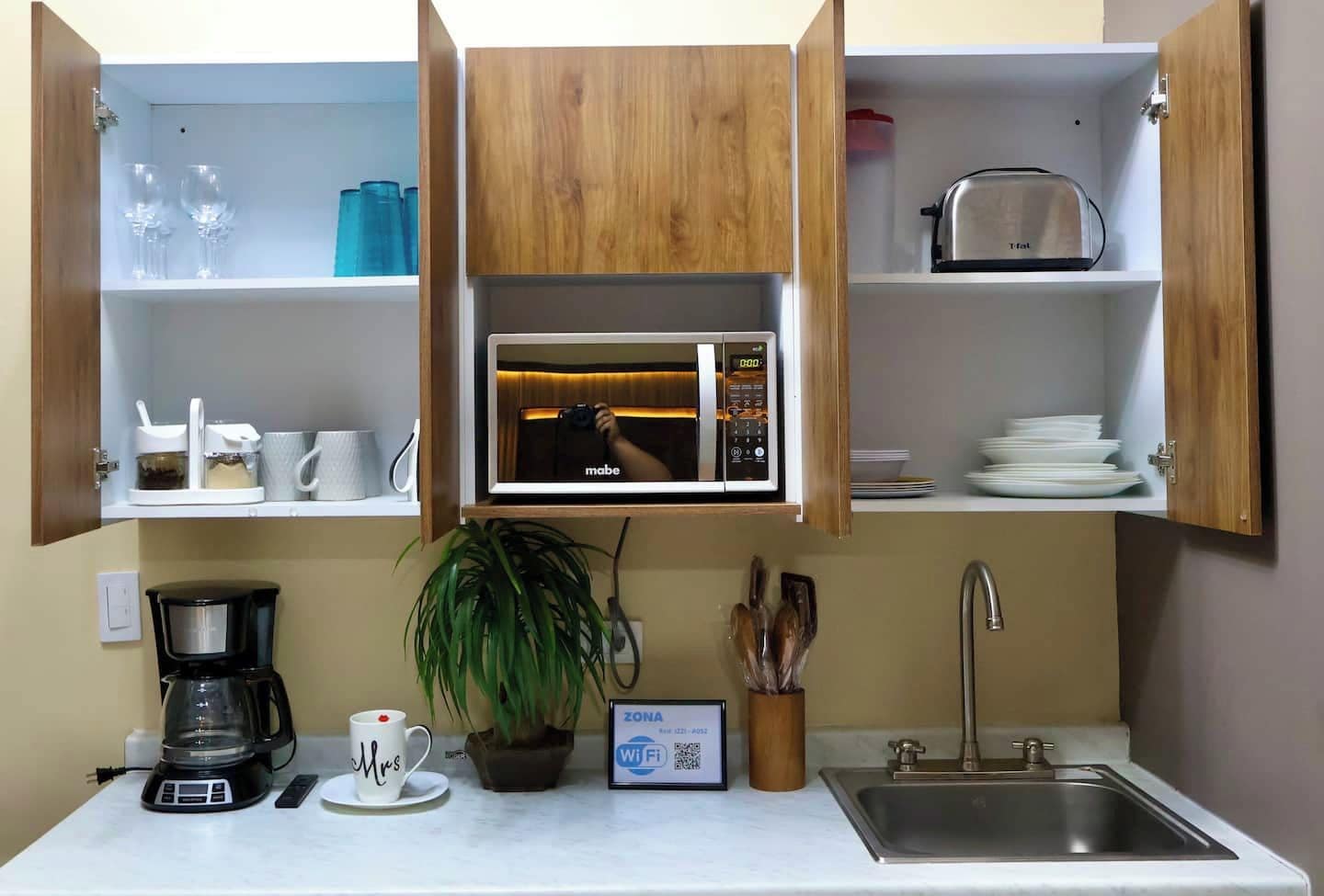 Cocina compacta con microondas, cafetera y lavabo.