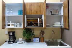 A compact kitchen with a microwave, coffee maker, and a sink. - Casa Arteaga (Monterrey)