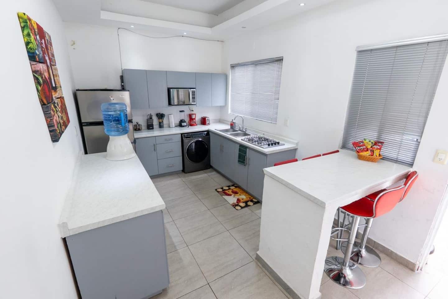 A compact kitchen with a microwave, sink, and a water dispenser.