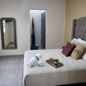 A hotel room with a bed, a mirror, a door, and a small plant. - Casa Arteaga (Monterrey)