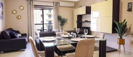 A modern dining area with a glass table, multiple chairs, and a sofa.