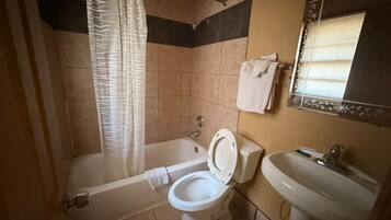 Et badeværelse med badekar, toilet og håndvask.