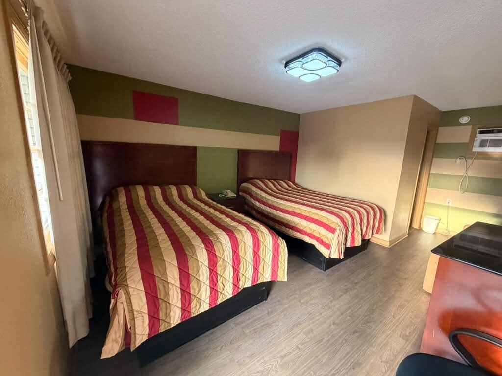 Una habitación con dos camas, un escritorio y una lámpara en el techo.