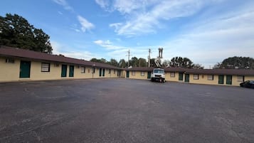 A motel with a parking lot, multiple motel units, and a clear sky.