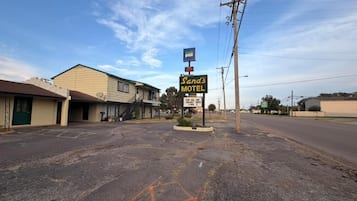 A motel with a signboard, a parking lot, and a building with a flat roof.