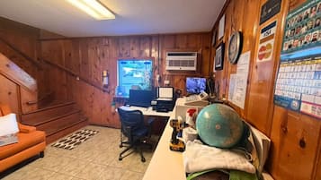 A room with a desk, computer, and a globe. There is a staircase and a wall calendar.