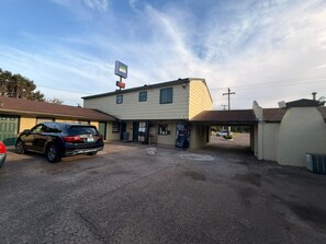 A motel with a parking lot, a car, and a signboard.