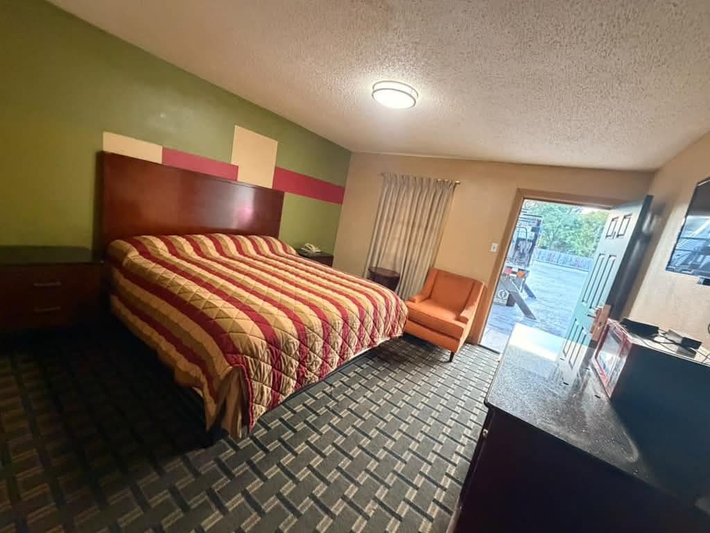Habitación de hotel con una cama, una silla, un escritorio y una ventana.