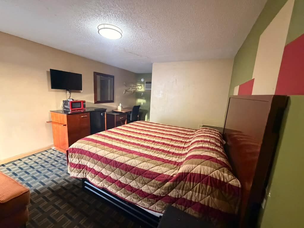Ein Hotelzimmer mit Bett, Schreibtisch, Fernseher und Mikrowelle.