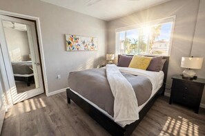 A bedroom with a bed, a nightstand, a window with a view, and a door leading to another room. - MISSION BEACH 1-bedroom w/ Large Ocean View Deck 714 (San Diego)