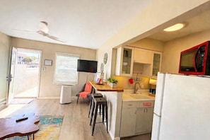 A compact kitchen with a flat-screen TV, a microwave, and a dishwasher. - MISSION BEACH 1-bedroom w/ Large Ocean View Deck 714 (San Diego)