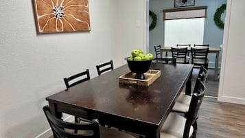 Ein Esszimmer mit einem dunklen Holztisch, sechs Stühlen und einer Schüssel grüner Äpfel auf dem Tisch.