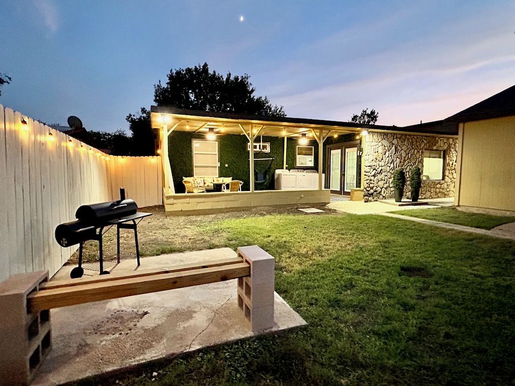 Un espace extérieur aménagé avec un patio, un barbecue, un coin salon couvert et un mur en pierre.