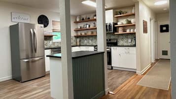 Une cuisine moderne avec un réfrigérateur en acier inoxydable, des armoires en bois et un îlot central vert.