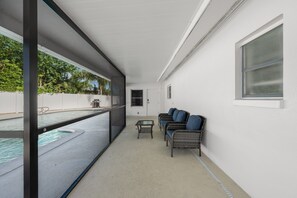 A balcony with a pool, a seating area with chairs, and a window. - Clearwater Pool Retreat | 3BR/3BA • Grill • Near B (Clearwater)