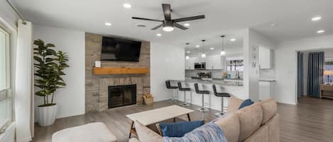 A modern living room with a fireplace, a sofa, a coffee table, and a TV mounted on the wall.