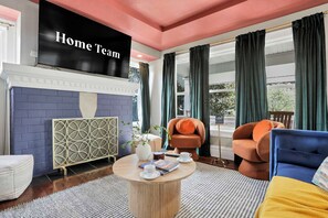 Ein modernes Wohnzimmer mit Kamin, einem Fernseher, der 'Home Team' zeigt, und einer Sitzecke mit Couchtisch.