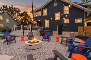 A backyard with a fire pit, outdoor seating, and a house with multiple windows. - The 614 Club Pool Hot Tub Fire Pit Games (Columbus)