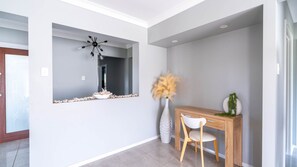 A modern interior with a wooden console table, a white chair, a decorative mirror, and a vase with pampas grass. - Hillside Residence ~ Picturesque mountain views with four spacious bedrooms (Nowra Hill)