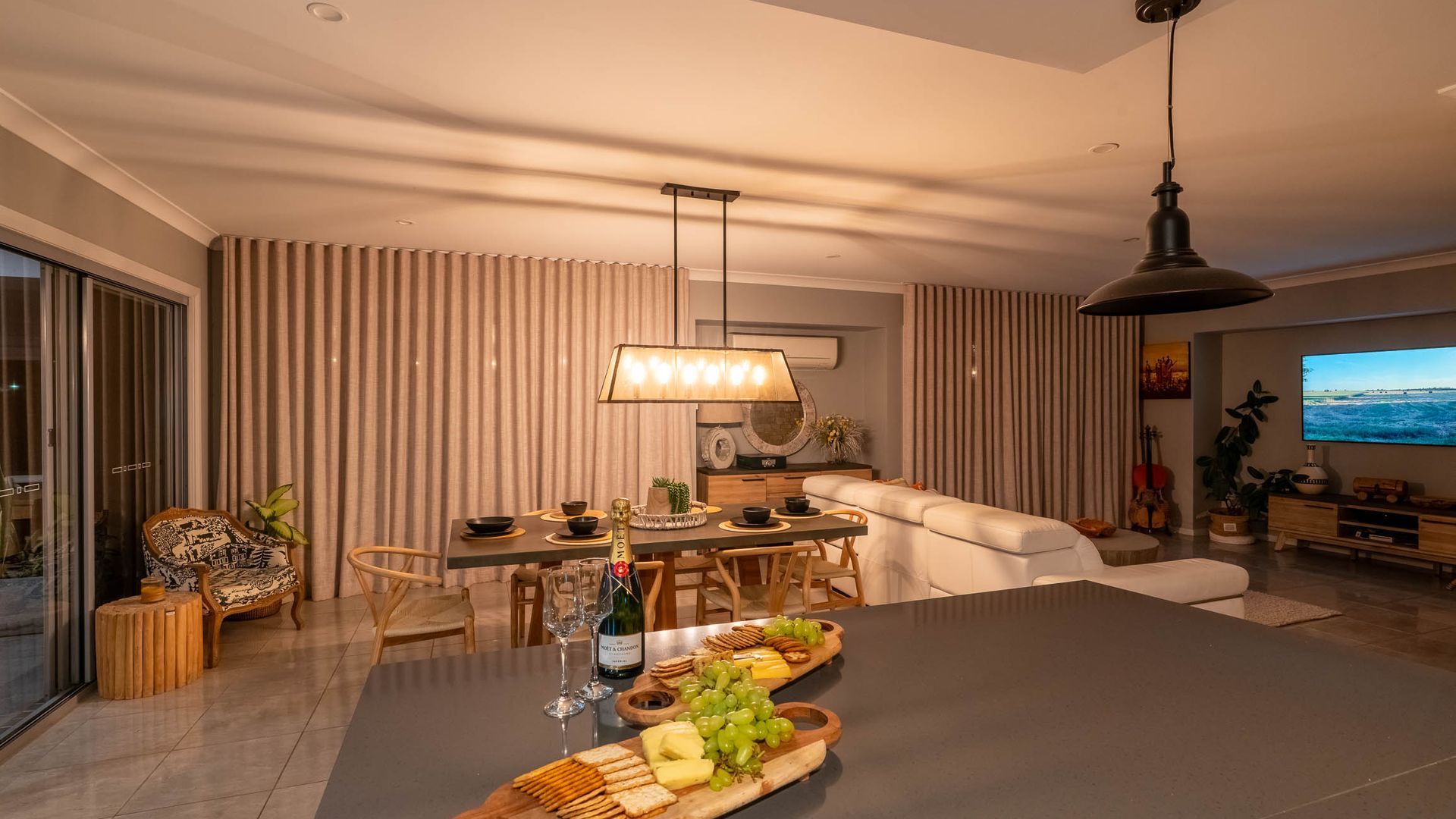 Una sala moderna con comedor, que incluye una mesa grande puesta para una comida, un sofá y un televisor.