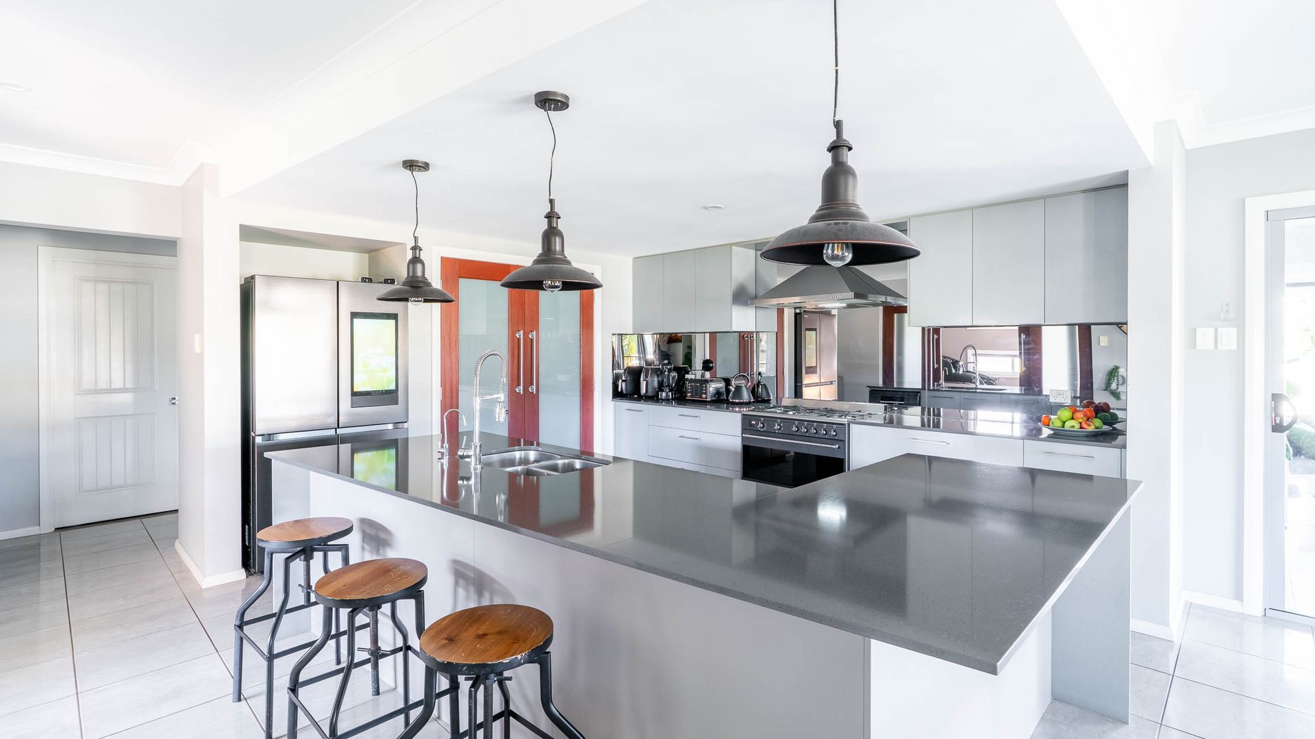 A modern kitchen with a large island, stainless steel appliances, and bar stools.