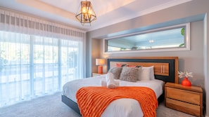 A modern bedroom with a large bed, a nightstand, a mirror, and a view of the outdoors. - Hillside Residence ~ Picturesque mountain views with four spacious bedrooms (Nowra Hill)