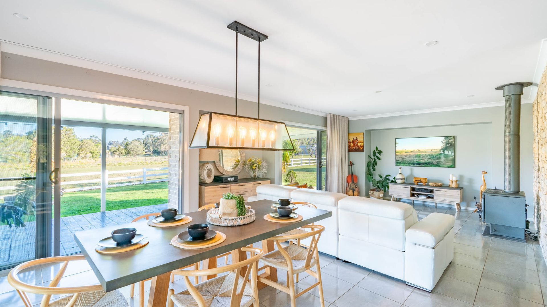 Un salon moderne comprenant un coin repas, une cheminée et une grande fenêtre donnant sur un jardin.