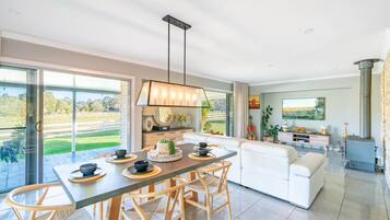 Un salon moderne comprenant un coin repas, une cheminée et une grande fenêtre donnant sur un jardin.